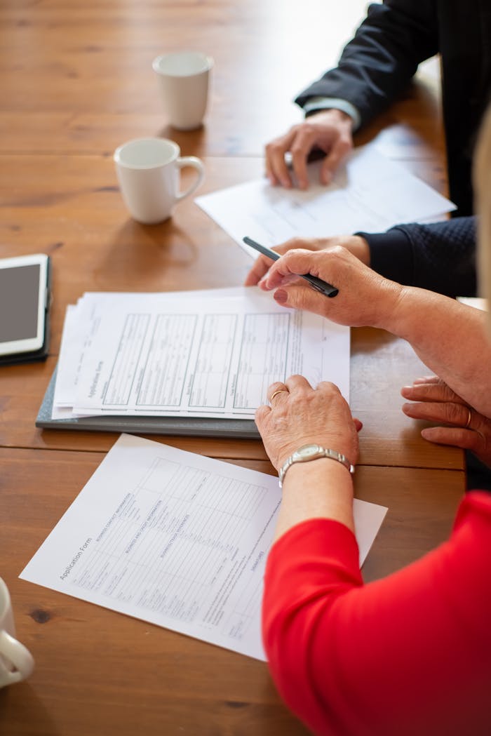 Business professionals reviewing contracts at a table, accompanied by coffee and a digital tablet.